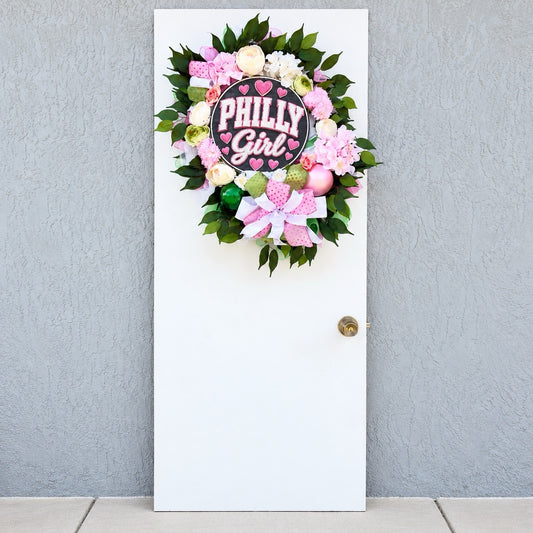 Philly Girl pink and green floral wreath displayed on a white front door with colorful flowers and a Philadelphia-inspired centerpiece.