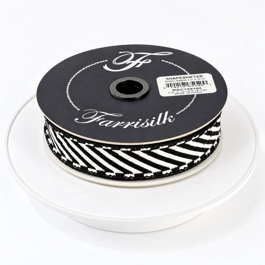 Farrisilk Shapeshifter black and white geometric wired ribbon, 1 inches wide, displayed on a full 10-yard spool with decorative ribbon loops.