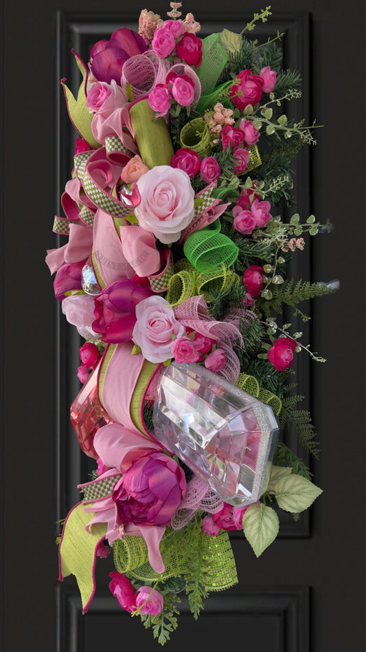 Pink floral gift box swag wreath with peonies, roses, green ribbon, and elegant front door decor