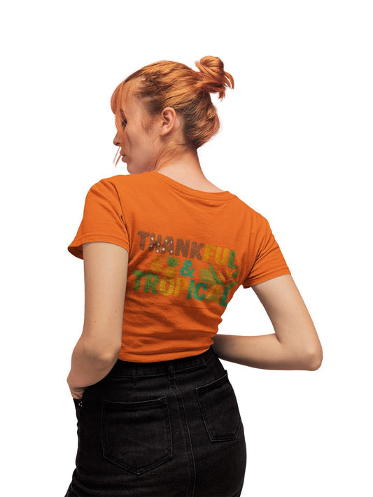 A bright and cheerful Caribbean-inspired design featuring the phrase “Thankful & Tropical.” The letters are textured to resemble soft, woven yarn in warm shades of brown, orange, green, and teal. Tropical elements like a pineapple, palm leaves, and a bird of paradise flower are integrated into the design, symbolizing warmth, gratitude, and island life. The background transitions smoothly from green to golden hues, evoking a tropical sunset glow.