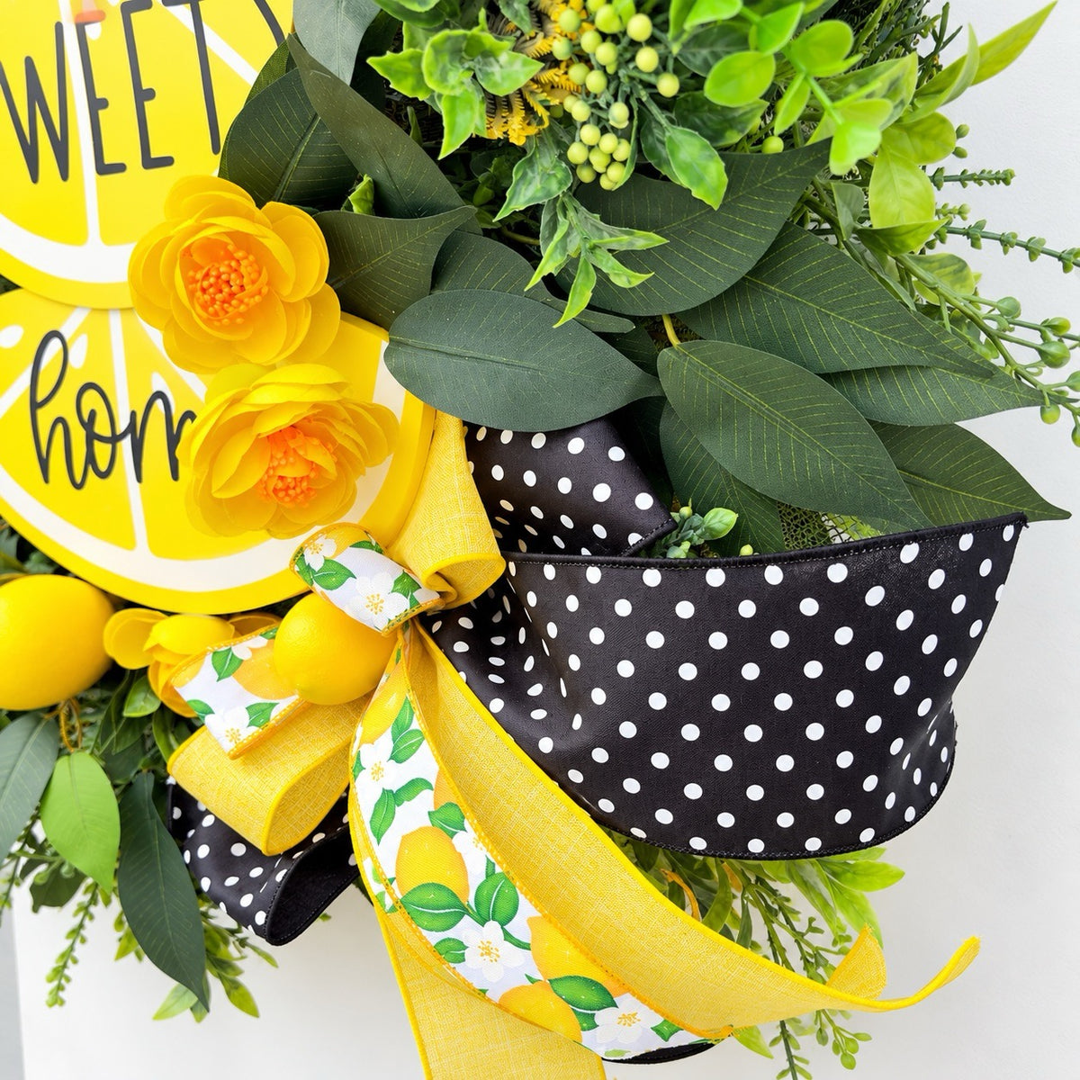 Handmade Lemon Sweet Home Summer Wreath featuring a yellow lemon-slice Home Sweet Home sign, bright yellow roses, decorative lemons, lush green foliage, and black-and-white polka-dot ribbon displayed on a white door.