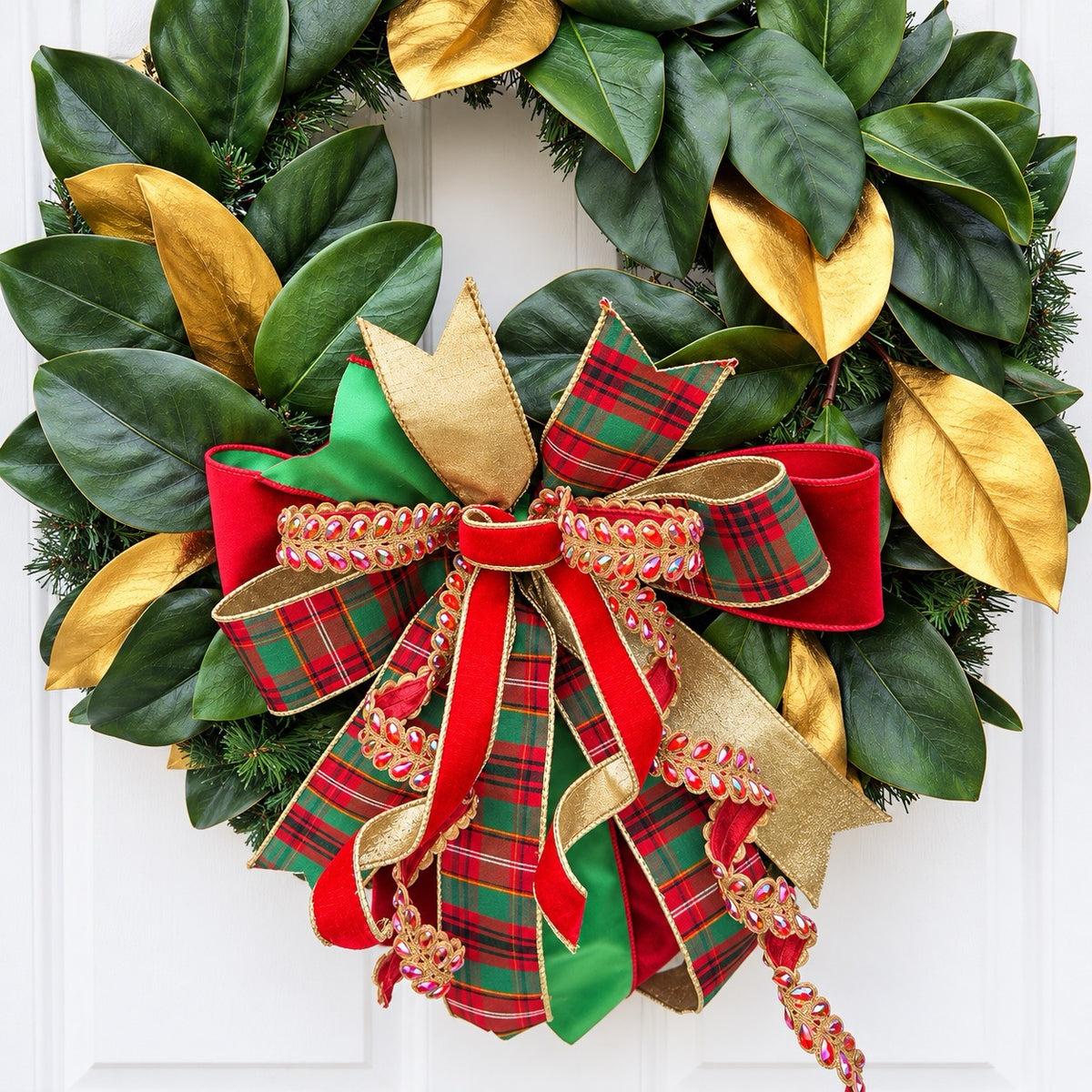 Handmade magnolia Christmas wreath with gold leaves and oversized red green tartan plaid and jeweled holiday bow