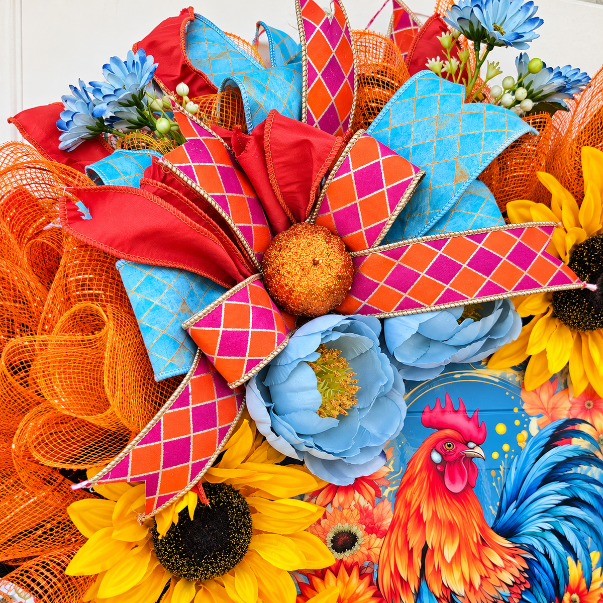 Handmade fall rooster wreath featuring vibrant yellow sunflowers, dusty blue flowers, orange deco mesh, coral and turquoise ribbons, and a colorful rooster centerpiece. A full farmhouse-style autumn wreath displayed on a white front door.