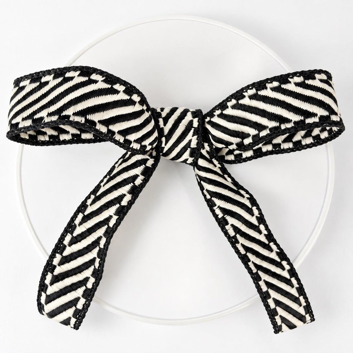 Farrisilk Shapeshifter black and white geometric wired ribbon, 1 inches wide, displayed on a full 10-yard spool with decorative ribbon loops.