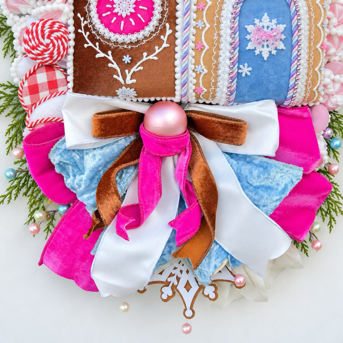 Sugarplum Gingerbread Cottage Christmas Wreath with pastel gingerbread house, pink and blue bows, poinsettias and Norfolk fir greenery.