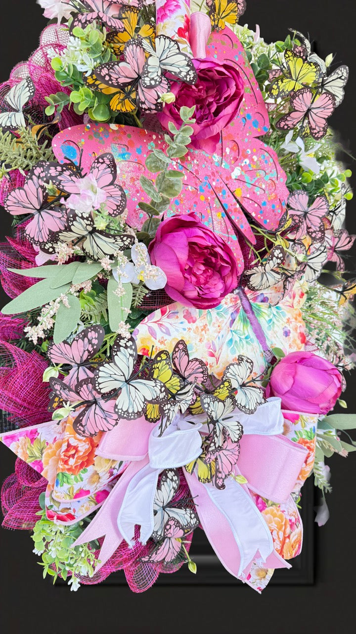 Handmade pink butterfly wreath featuring vibrant florals, layered designer ribbons, lush greenery, and colorful butterflies. This whimsical spring and summer front door wreath creates a beautiful statement piece perfect for entryways, porch decor, and everyday home decorating.
