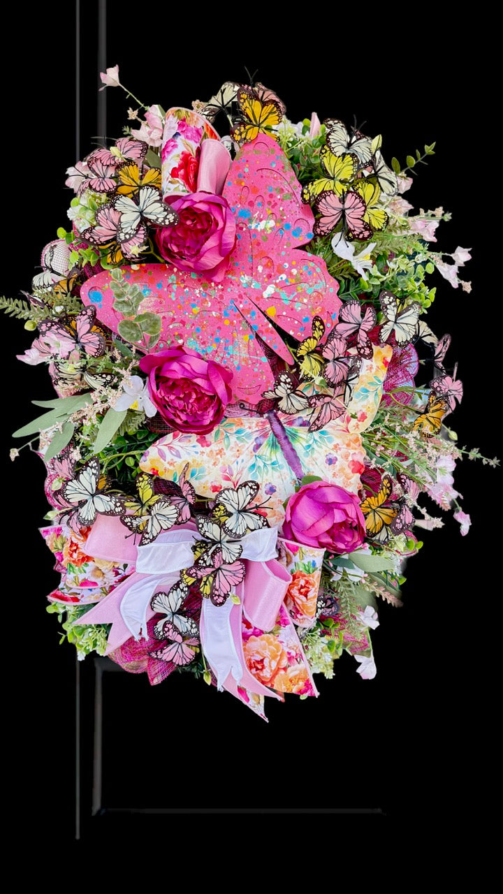 Handmade pink butterfly wreath featuring vibrant florals, layered designer ribbons, lush greenery, and colorful butterflies. This whimsical spring and summer front door wreath creates a beautiful statement piece perfect for entryways, porch decor, and everyday home decorating.