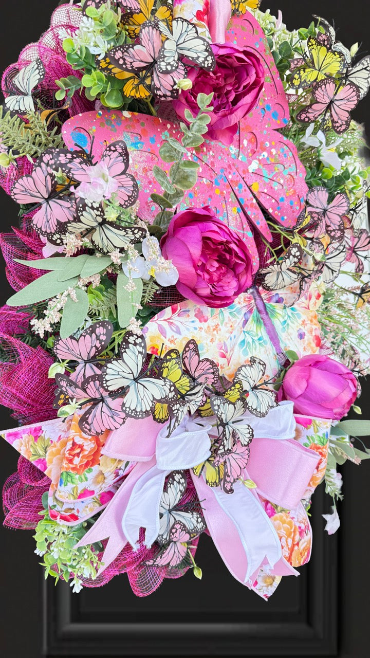Handmade pink butterfly wreath featuring vibrant florals, layered designer ribbons, lush greenery, and colorful butterflies. This whimsical spring and summer front door wreath creates a beautiful statement piece perfect for entryways, porch decor, and everyday home decorating.