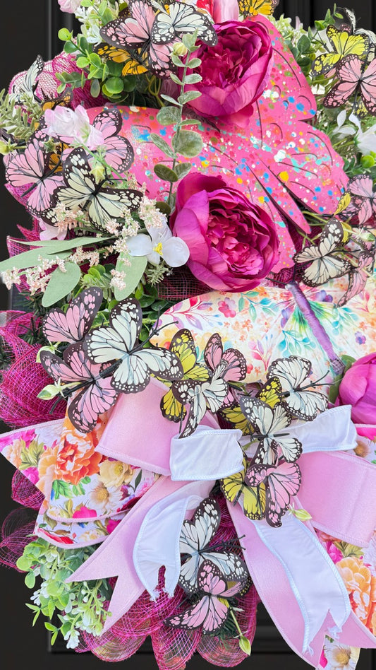 Handmade pink butterfly wreath featuring vibrant florals, layered designer ribbons, lush greenery, and colorful butterflies. This whimsical spring and summer front door wreath creates a beautiful statement piece perfect for entryways, porch decor, and everyday home decorating.