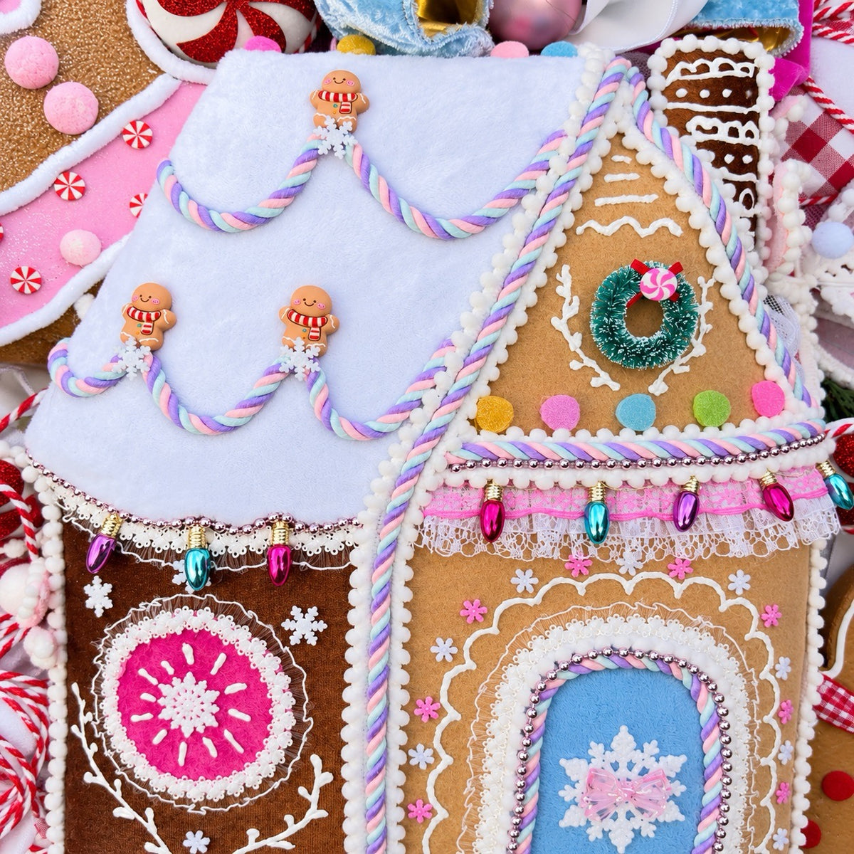 Sugarplum Gingerbread Cottage Christmas Wreath with pastel gingerbread house, pink and blue bows, poinsettias and Norfolk fir greenery.