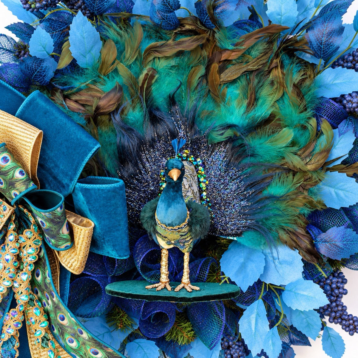 Close-up of ornate teal peacock centerpiece with decorative feathers, gold accents, and shimmering details.