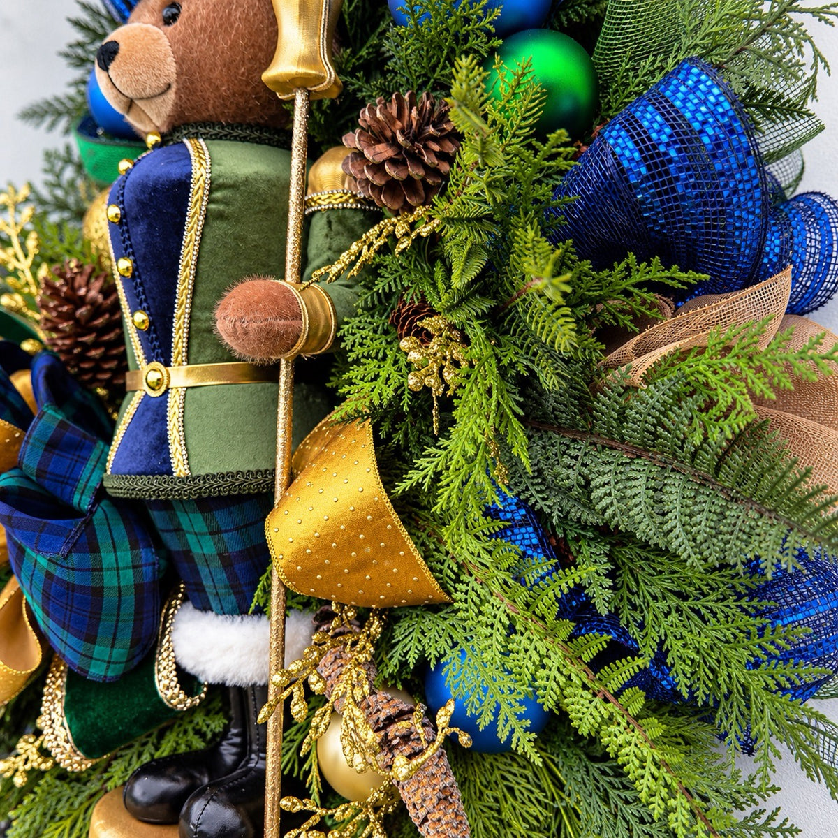 Detail of navy and gold ornaments, frosted pinecones and gold berries.