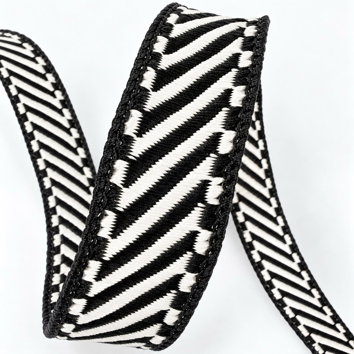 Farrisilk Shapeshifter black and white geometric wired ribbon, 1 inches wide, displayed on a full 10-yard spool with decorative ribbon loops.