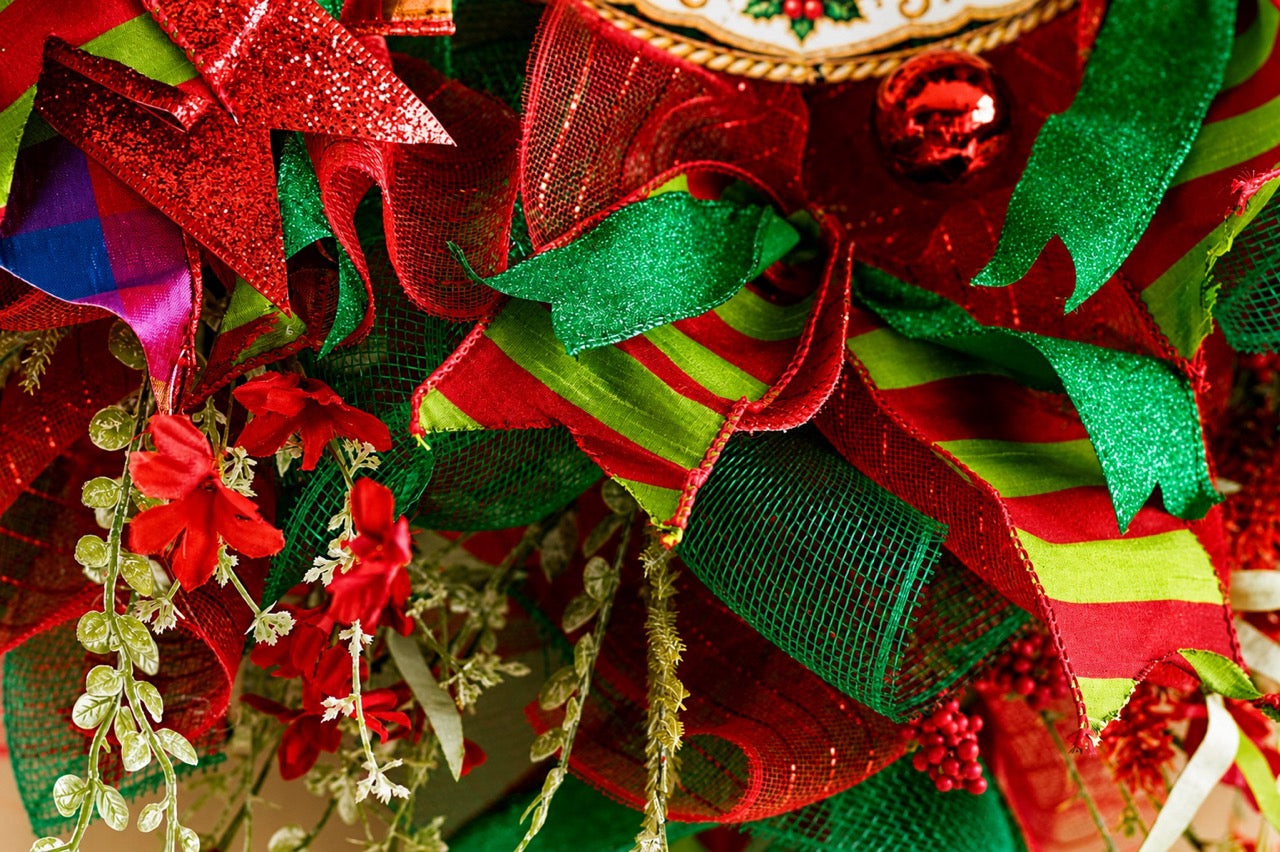 Handcrafted red and emerald green Nutcracker Christmas wreath with Merry Christmas centerpiece, glitter ribbon, ornaments, berries, mesh, and gold accents.