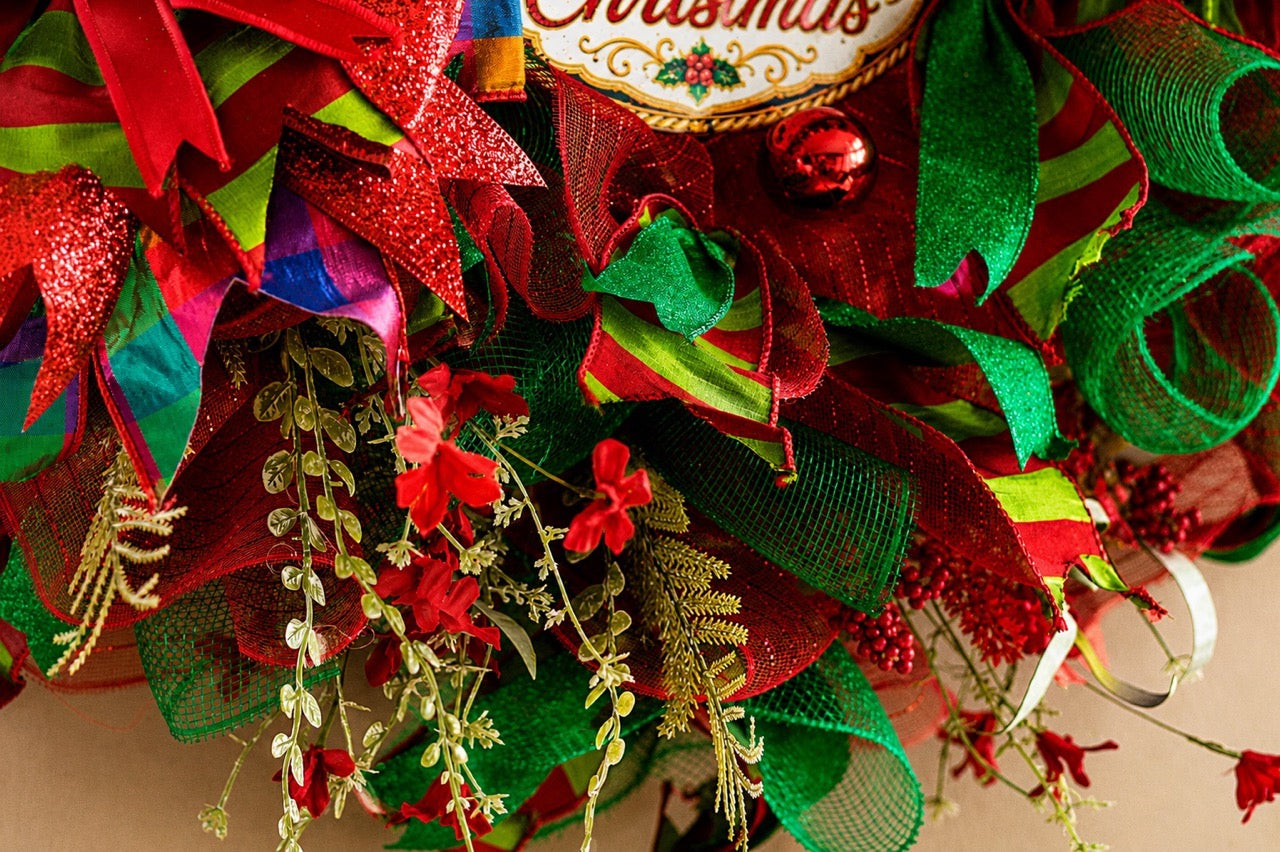 Handcrafted red and emerald green Nutcracker Christmas wreath with Merry Christmas centerpiece, glitter ribbon, ornaments, berries, mesh, and gold accents.