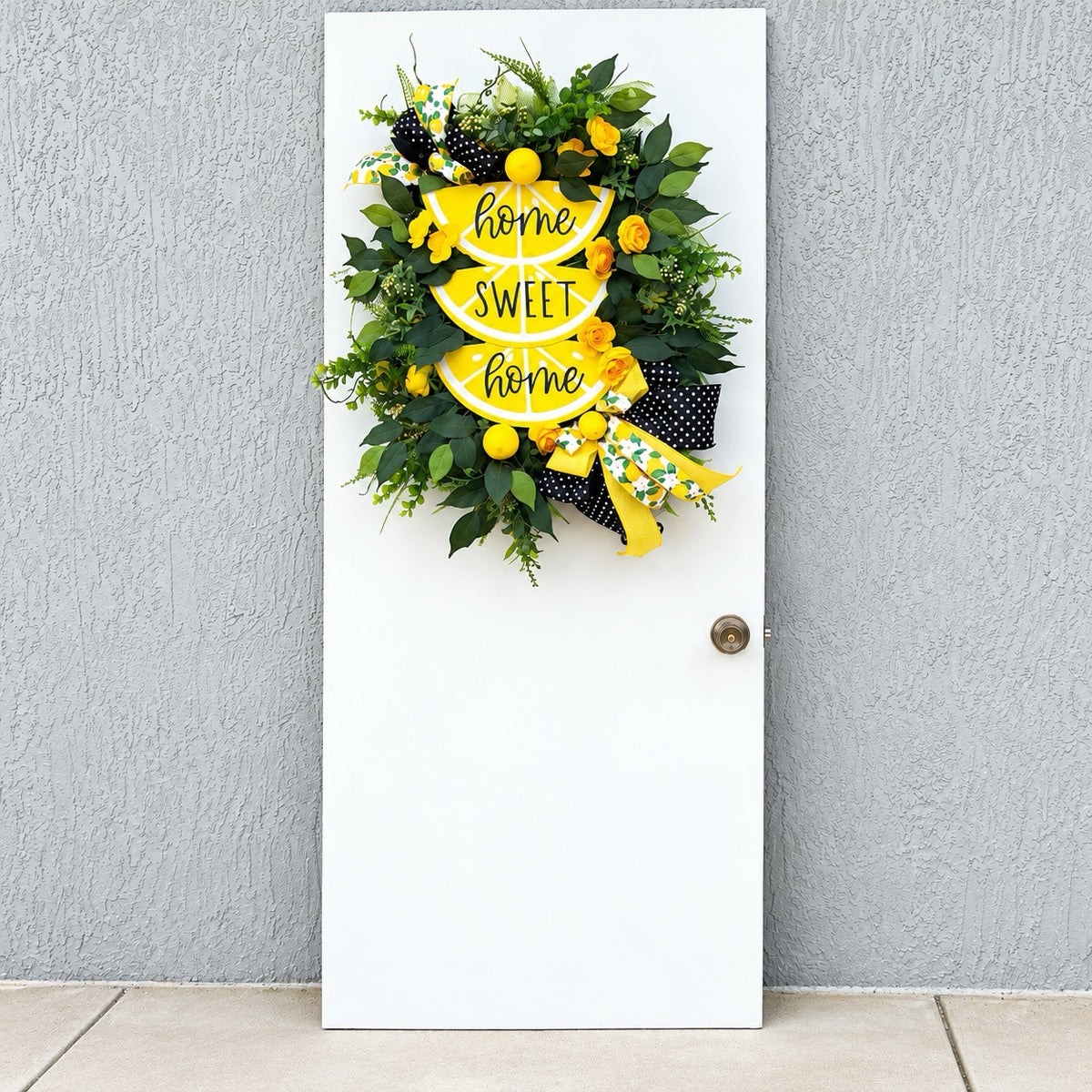 Handmade Lemon Sweet Home Summer Wreath featuring a yellow lemon-slice Home Sweet Home sign, bright yellow roses, decorative lemons, lush green foliage, and black-and-white polka-dot ribbon displayed on a white door.