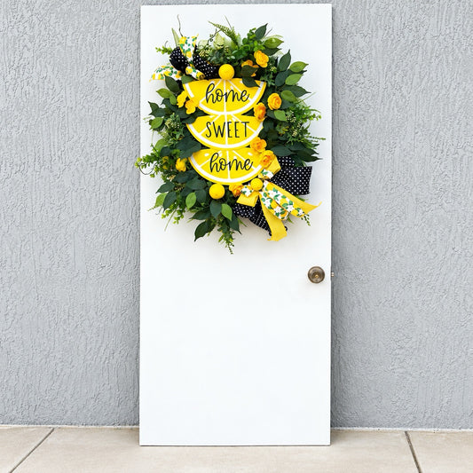 Handmade Lemon Sweet Home Summer Wreath featuring a yellow lemon-slice Home Sweet Home sign, bright yellow roses, decorative lemons, lush green foliage, and black-and-white polka-dot ribbon displayed on a white door.