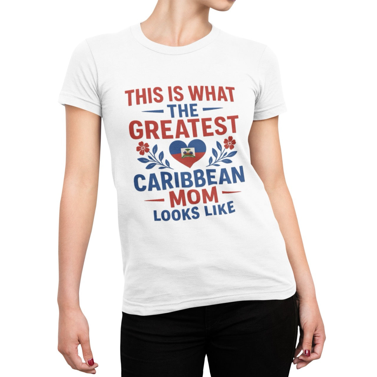 Woman wearing a pink T-shirt with bold red and blue text reading “This is what the greatest Caribbean mom looks like,” featuring a heart with the Haitian flag and floral accents.