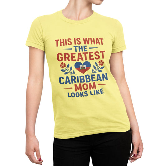 Woman wearing a pink T-shirt with bold red and blue text reading “This is what the greatest Caribbean mom looks like,” featuring a heart with the Haitian flag and floral accents.