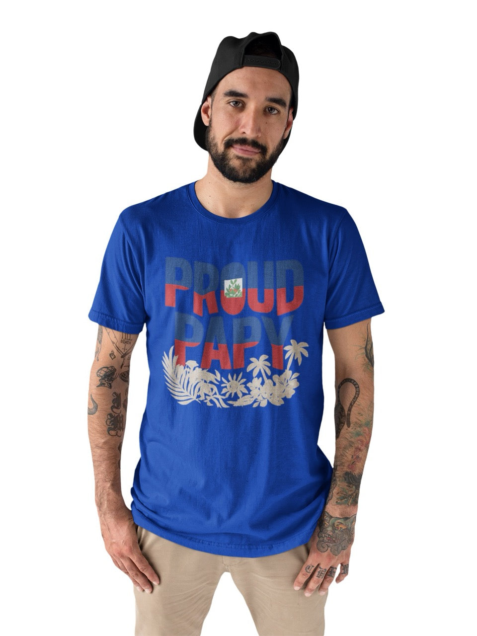 Man wearing a navy T-shirt with bold text reading “Proud Papy,” featuring Haitian flag colors and tropical floral accents.