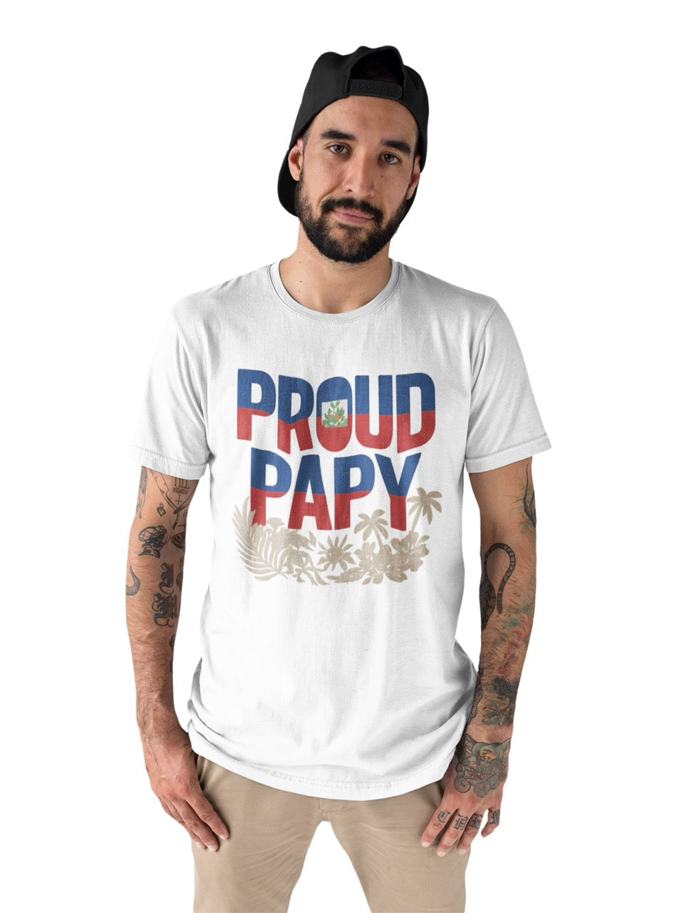 Man wearing a white T-shirt with bold text reading “Proud Papy,” featuring Haitian flag colors and tropical floral accents.