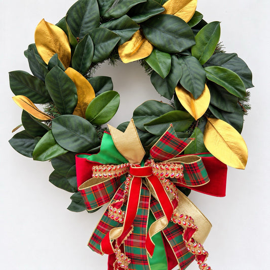 Handmade magnolia Christmas wreath with gold leaves and oversized red green tartan plaid and jeweled holiday bow