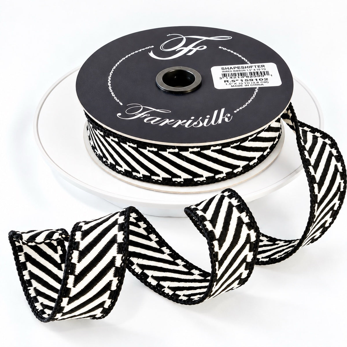 Farrisilk Shapeshifter black and white geometric wired ribbon, 1 inches wide, displayed on a full 10-yard spool with decorative ribbon loops.