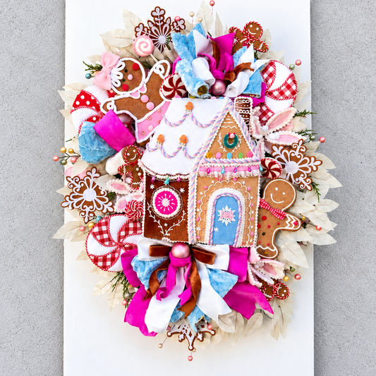 Sugarplum Gingerbread Cottage Christmas Wreath with pastel gingerbread house, pink and blue bows, poinsettias and Norfolk fir greenery.