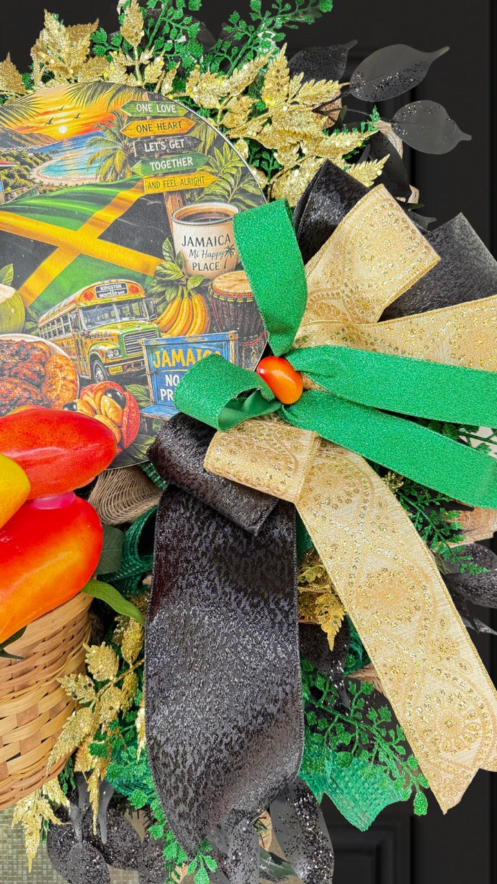 Luxury handmade Jamaica-inspired door wreath featuring green, black, and gold designer ribbons, tropical fruit basket, glittered foliage, and colorful island-themed artwork celebrating Jamaican culture and Caribbean décor.