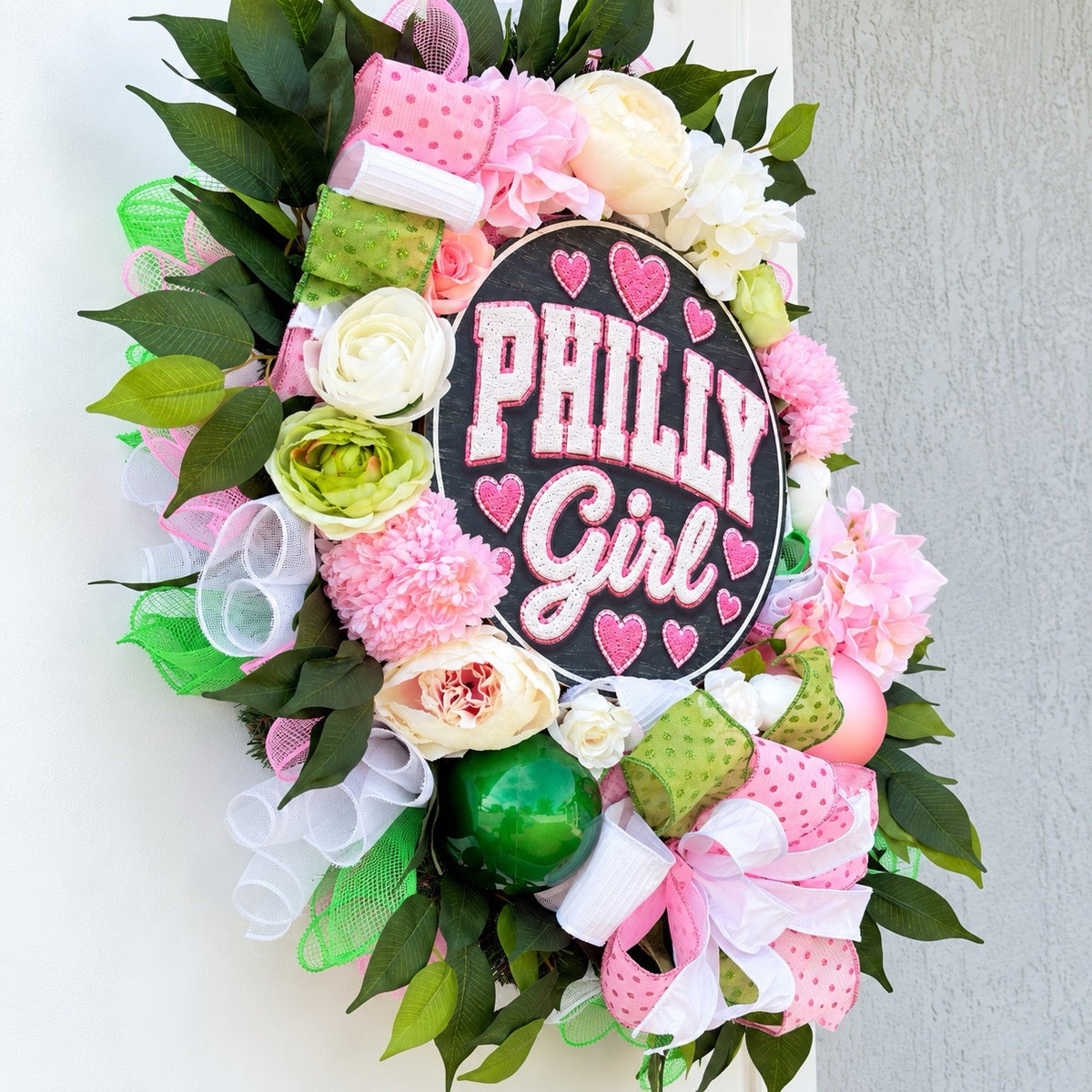 Side view of handmade Philly Girl wreath showing dimensional flowers, decorative ornaments, and layered greenery.