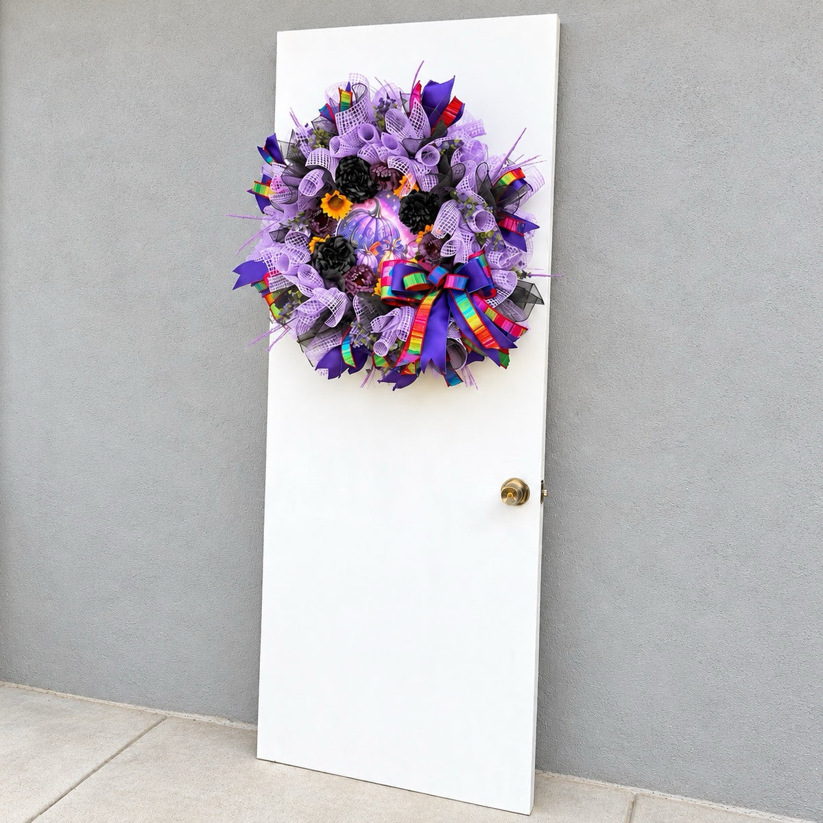 Velvet Eclipse purple Halloween wreath styled on a white door with gray textured wall