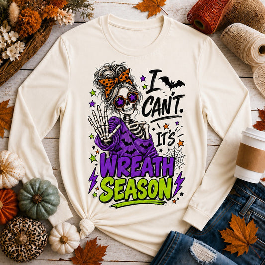 Close-up of funny fall skeleton tee reading "I Can't. It's Wreath Season" in purple and lime-green lettering