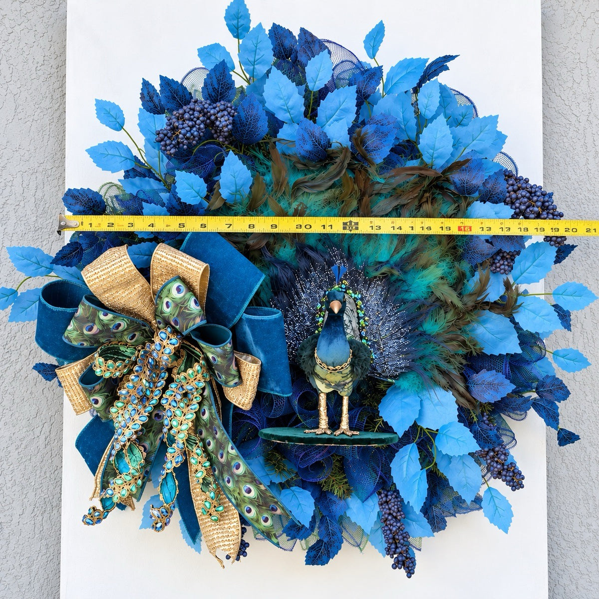 Full view of handmade peacock wreath with measuring tape showing the finished dimensions.