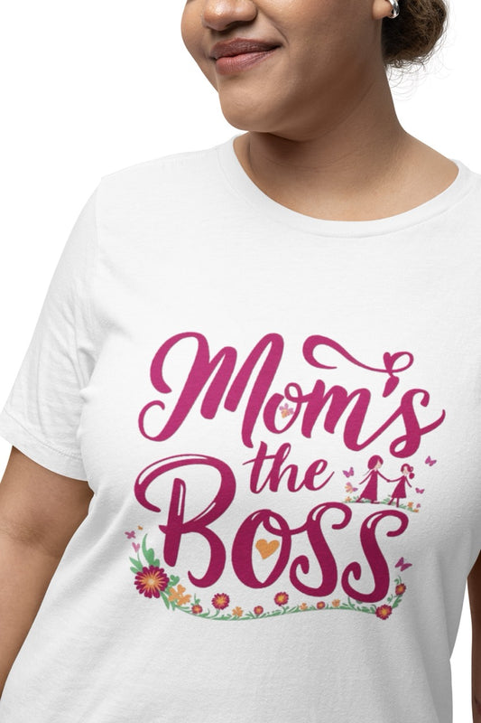 Woman wearing a white T-shirt with bold pink script reading “Mom’s the Boss,” decorated with flowers, hearts, and a small illustration of a mother and child.