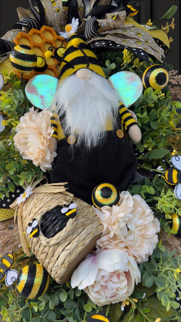 Luxury bee-themed door swag featuring a whimsical bee gnome, honeycomb decoration, beehive accent, premium black and yellow ribbons, lush greenery, cream florals, and sparkling bee embellishments, perfect for spring and summer front door décor.