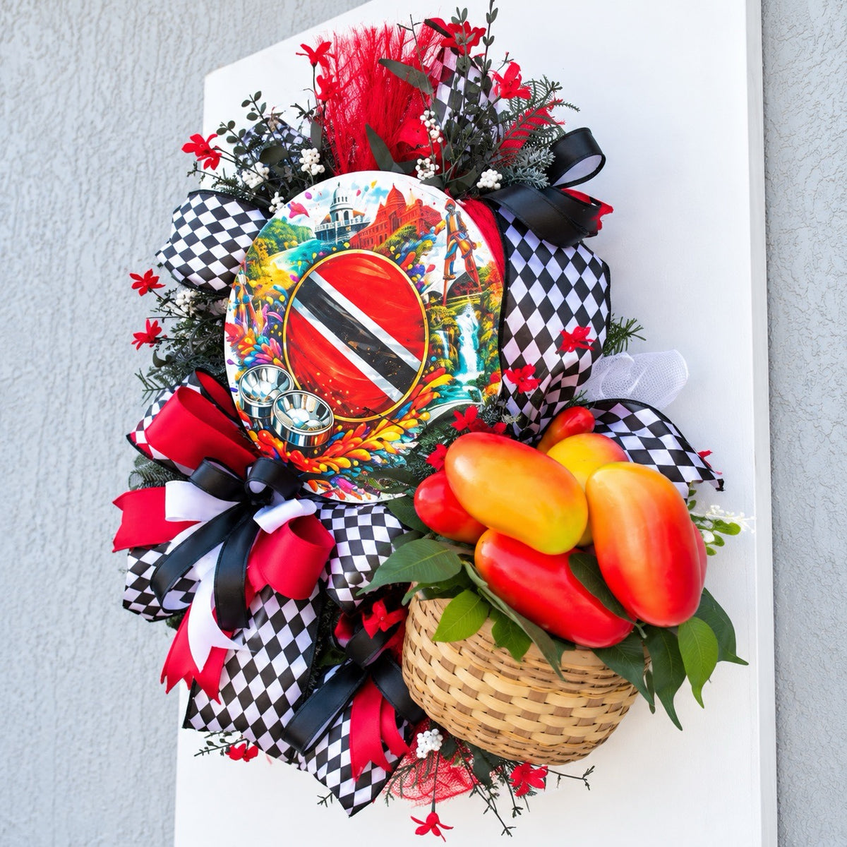 Angled right view of Caribbean wreath featuring a woven basket of colorful tropical peppers, black and white patterned ribbons and lush decorative greenery.