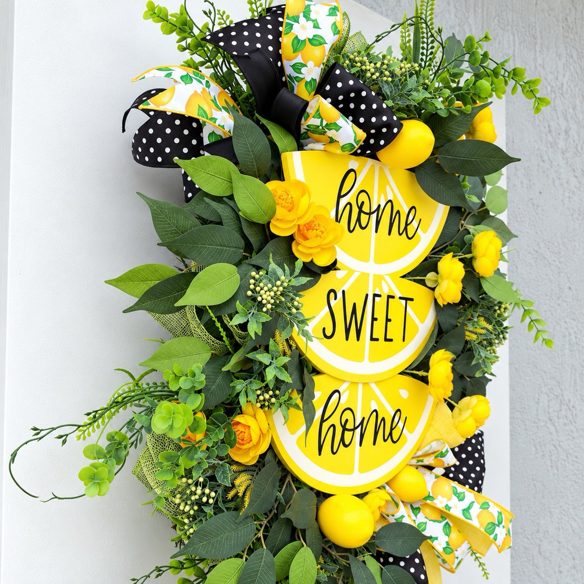Handmade Lemon Sweet Home Summer Wreath featuring a yellow lemon-slice Home Sweet Home sign, bright yellow roses, decorative lemons, lush green foliage, and black-and-white polka-dot ribbon displayed on a white door.