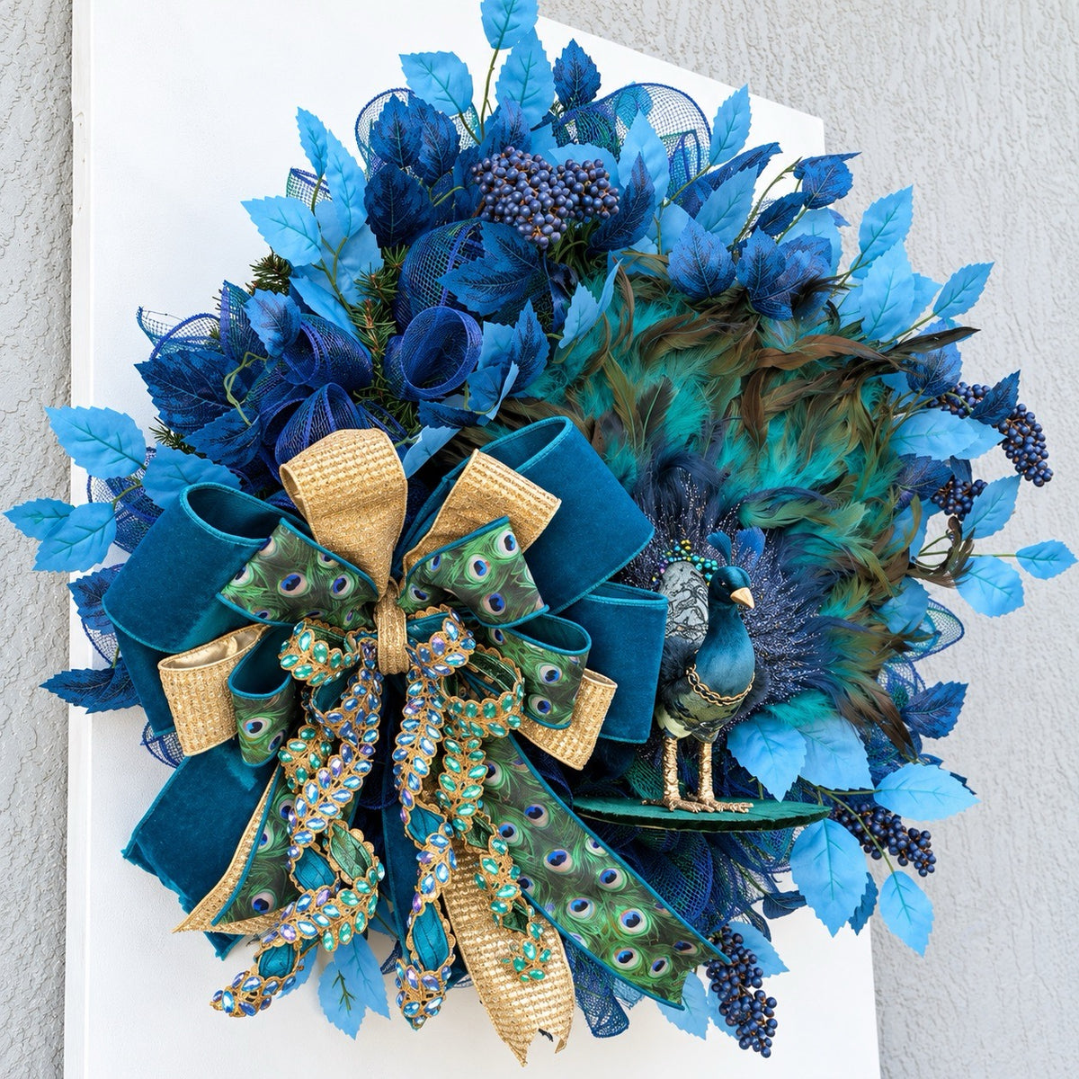 Side view of handmade peacock wreath showing layered foliage, feather depth, and dimensional construction.