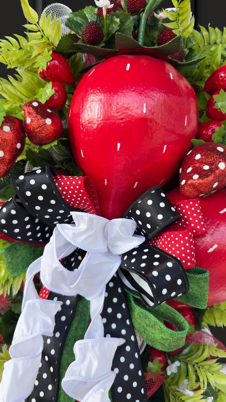 Luxury handmade strawberry door swag with oversized red strawberries, glitter strawberry ornaments, bright green foliage, white flowers, and a designer black, red, white, and green ribbon bow, perfect for summer front door décor and farmhouse-style decorating. 🍓✨