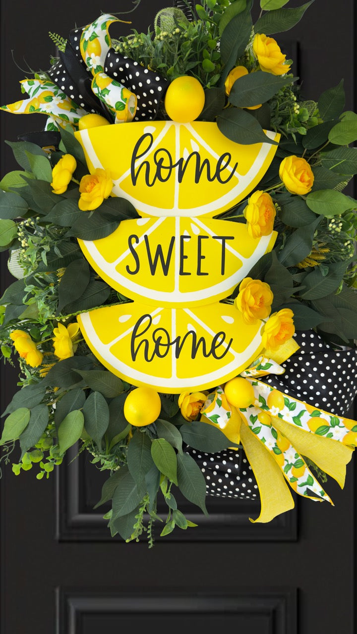 Handmade summer lemon wreath with stacked lemon slice signs reading ‘Home Sweet Home,’ decorated with yellow flowers, faux lemons, greenery, and polka‑dot and lemon‑print ribbons