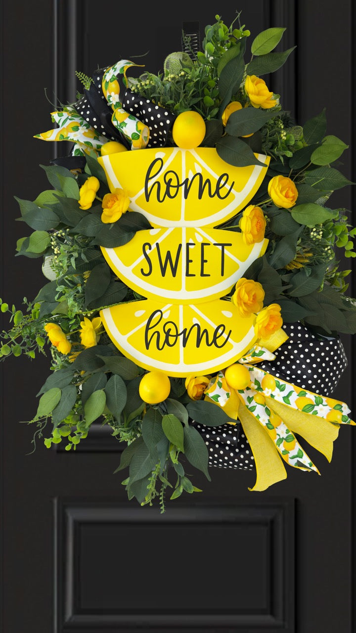 Handmade summer lemon wreath with stacked lemon slice signs reading ‘Home Sweet Home,’ decorated with yellow flowers, faux lemons, greenery, and polka‑dot and lemon‑print ribbons