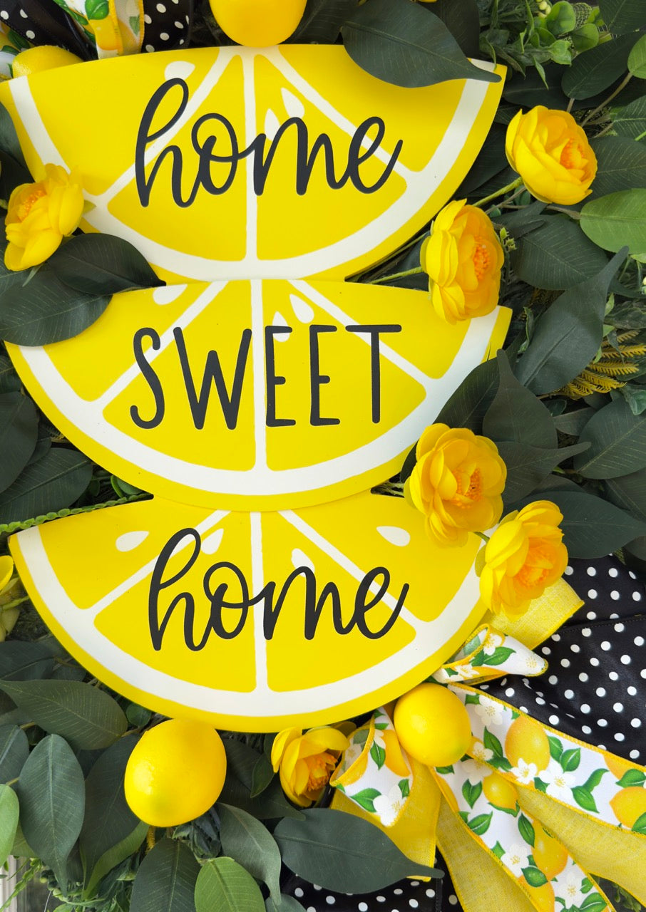 Handmade summer lemon wreath with stacked lemon slice signs reading ‘Home Sweet Home,’ decorated with yellow flowers, faux lemons, greenery, and polka‑dot and lemon‑print ribbons