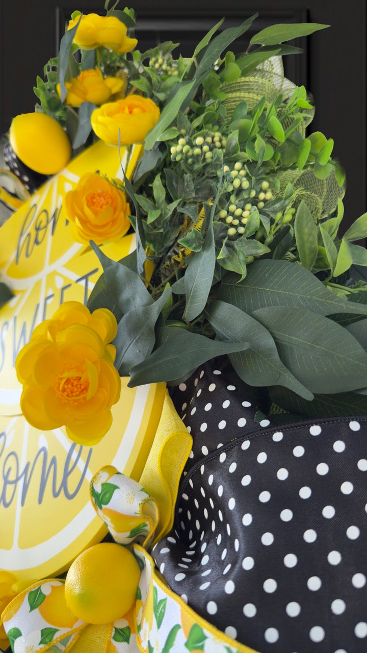 Handmade summer lemon wreath with stacked lemon slice signs reading ‘Home Sweet Home,’ decorated with yellow flowers, faux lemons, greenery, and polka‑dot and lemon‑print ribbons