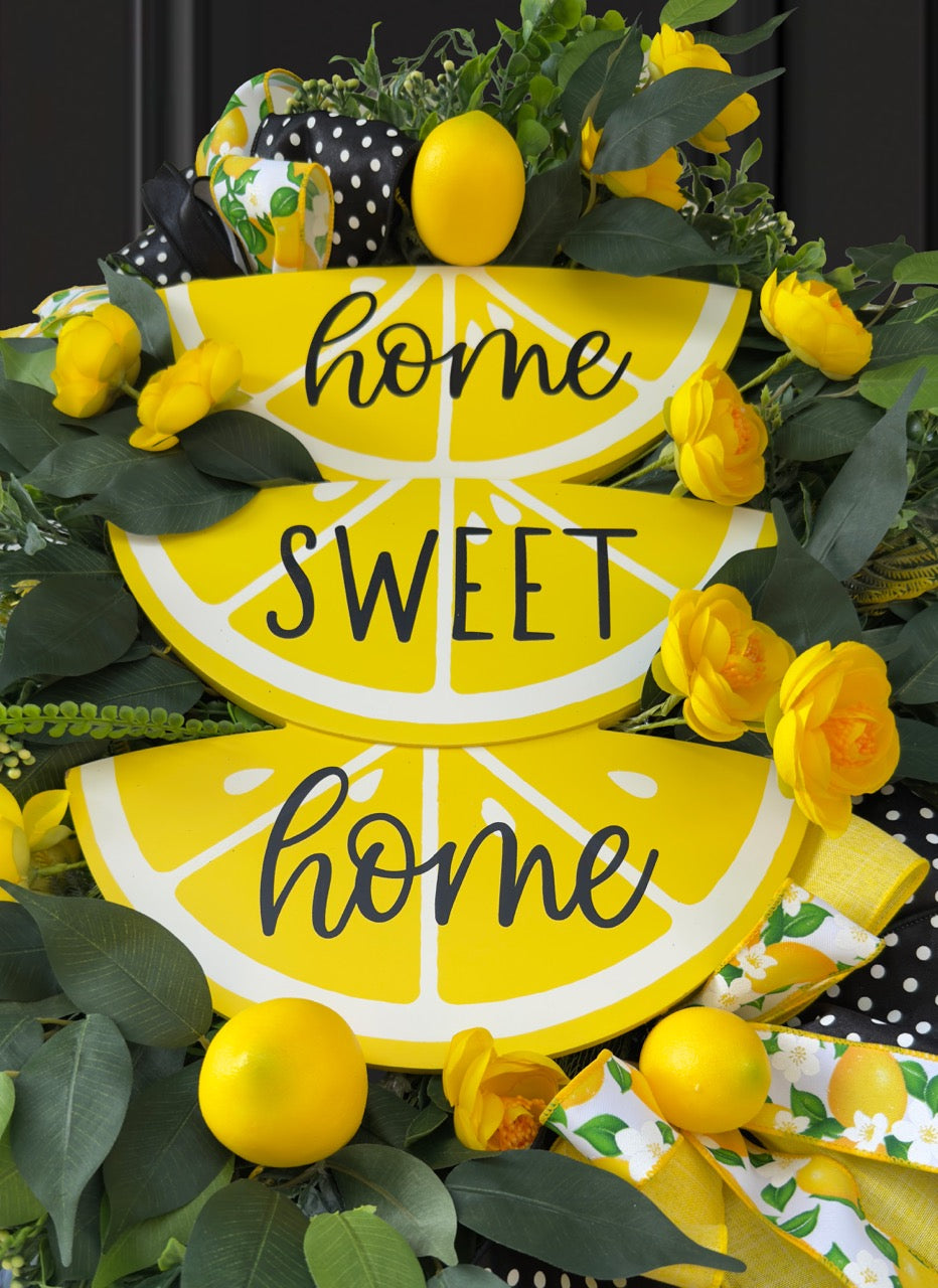Handmade summer lemon wreath with stacked lemon slice signs reading ‘Home Sweet Home,’ decorated with yellow flowers, faux lemons, greenery, and polka‑dot and lemon‑print ribbons