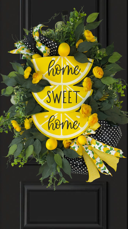 Handmade summer lemon wreath with stacked lemon slice signs reading ‘Home Sweet Home,’ decorated with yellow flowers, faux lemons, greenery, and polka‑dot and lemon‑print ribbons