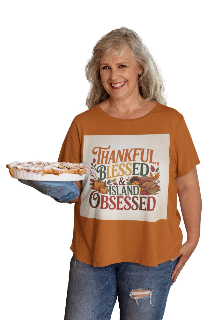 A cheerful Caribbean-inspired Thanksgiving design featuring the phrase “Thankful, Blessed & Island Obsessed.” The text is styled in bold autumn colors — orange, gold, green, and deep red — surrounded by pumpkins, colorful fall leaves, and a cornucopia overflowing with fruits and vegetables. The design beautifully blends traditional Thanksgiving symbols with tropical warmth, celebrating gratitude and island pride.