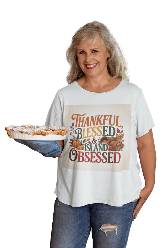 A cheerful Caribbean-inspired Thanksgiving design featuring the phrase “Thankful, Blessed & Island Obsessed.” The text is styled in bold autumn colors — orange, gold, green, and deep red — surrounded by pumpkins, colorful fall leaves, and a cornucopia overflowing with fruits and vegetables. The design beautifully blends traditional Thanksgiving symbols with tropical warmth, celebrating gratitude and island pride.