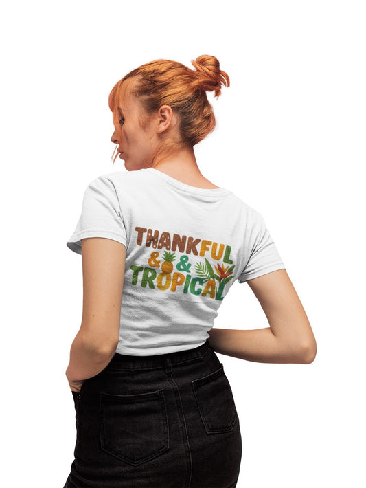 A bright and cheerful Caribbean-inspired design featuring the phrase “Thankful & Tropical.” The letters are textured to resemble soft, woven yarn in warm shades of brown, orange, green, and teal. Tropical elements like a pineapple, palm leaves, and a bird of paradise flower are integrated into the design, symbolizing warmth, gratitude, and island life. The background transitions smoothly from green to golden hues, evoking a tropical sunset glow.