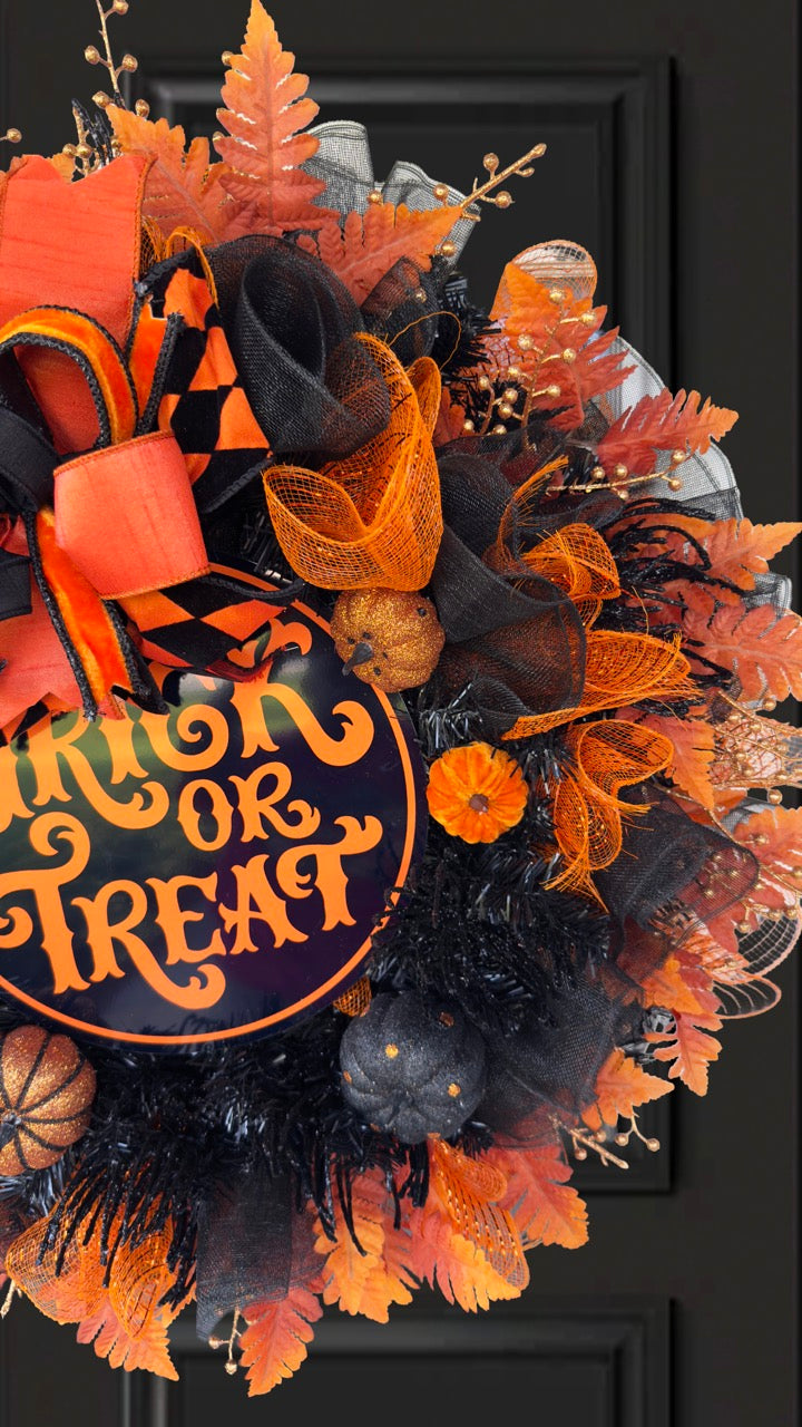 Black and orange Halloween wreath with layered mesh, designer ribbons, fall leaves, glitter pumpkins, and a round “Trick or Treat” sign.