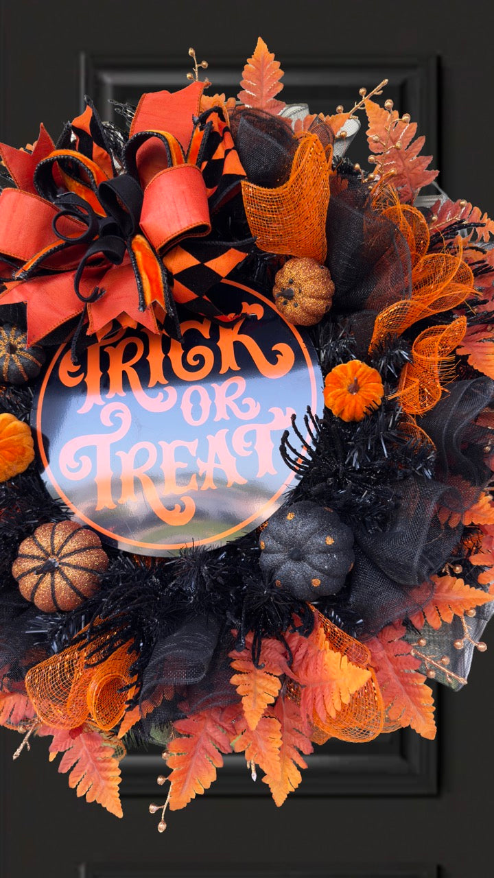 Black and orange Halloween wreath with layered mesh, designer ribbons, fall leaves, glitter pumpkins, and a round “Trick or Treat” sign.